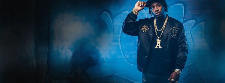 Person wearing a dark jacket with  gold chains, gold braclets, rings and hat in a blue-lit room